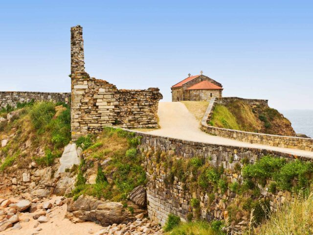 Restos de la fortaleza de A Lanzada con la ermita al fondo